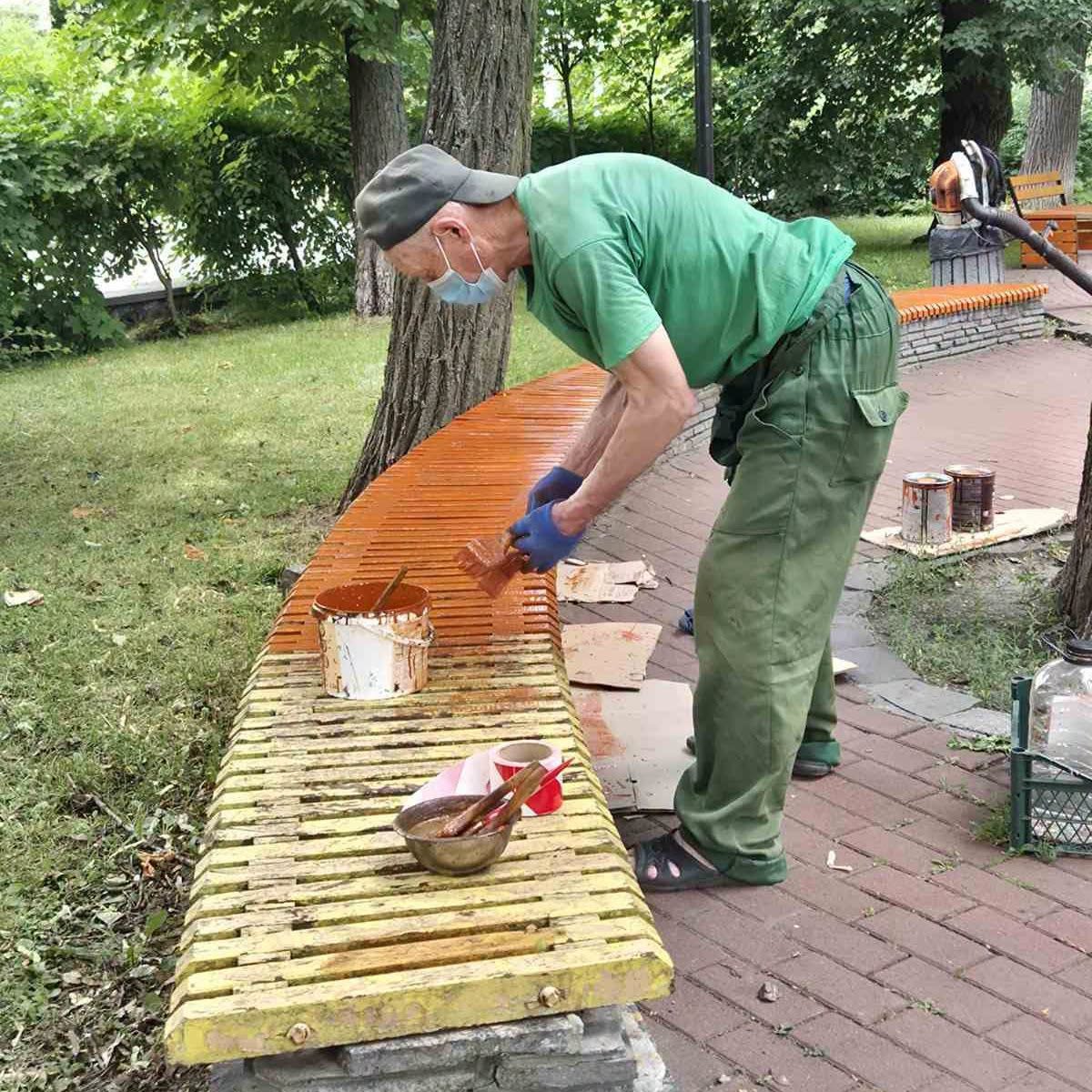 Комунальні працівники фарбують лавки у парку