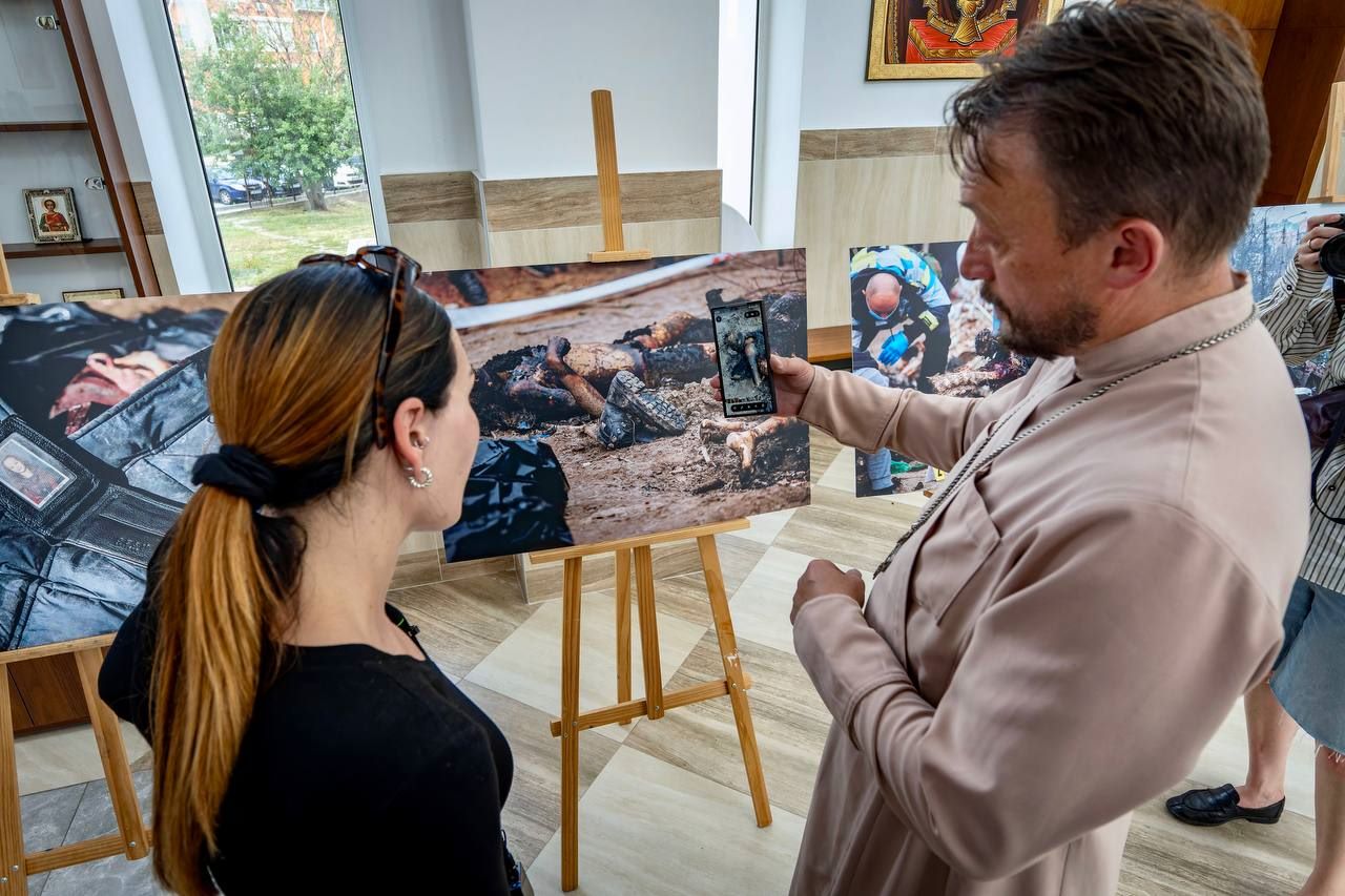 Лумер та настоятель храму у Бучі біля світлин, де задокументовані воєнні злочини російських окупантів