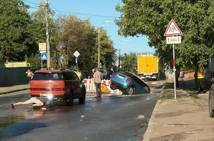 У Подільському районі Києва авто провалилося у яму через аварію на водогоні (фото)