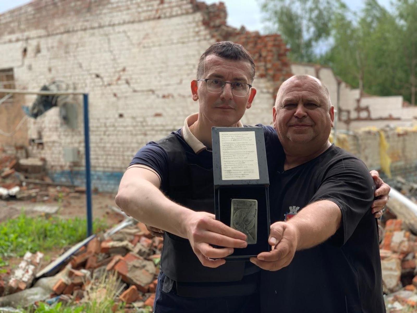 Ювілейна медаль до сторіччя Міжнародної федерації журналістів вручається хороброму редактору на фундаменті розбитого магазину. Голова НСЖУ Сергій Томіленко та головний редактор «Ворскли» Олексій Пасюга