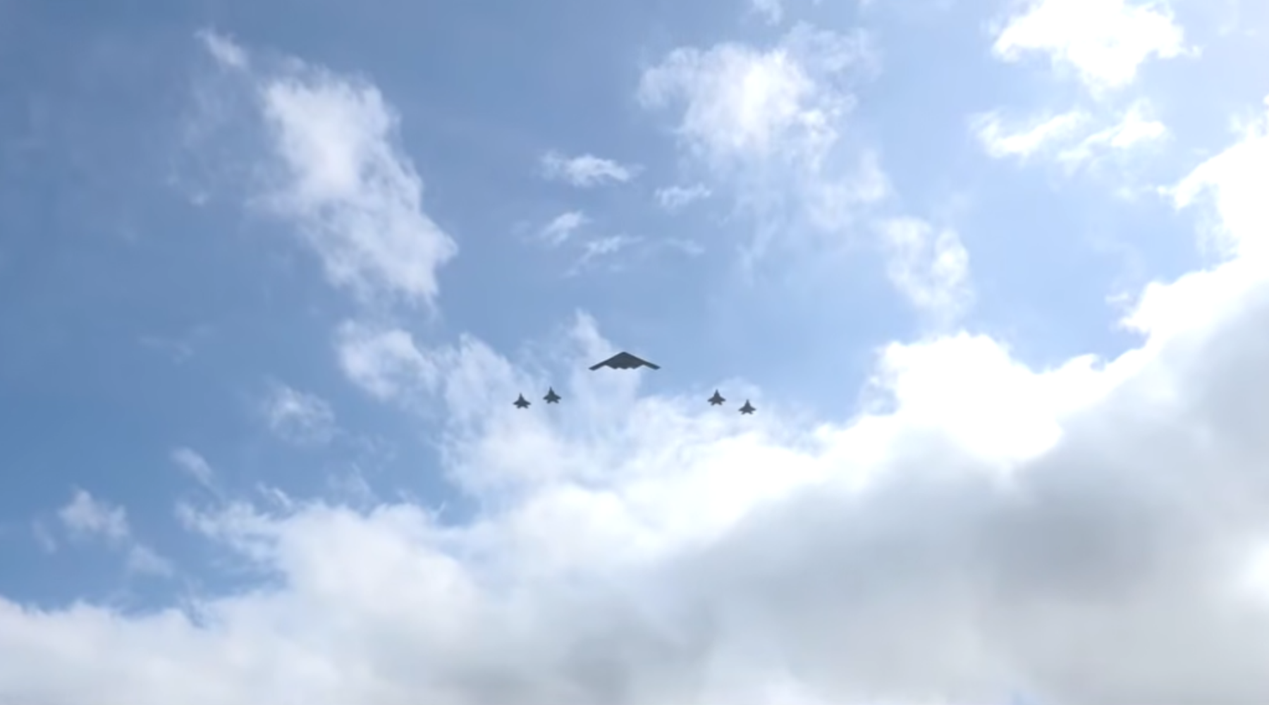 Cтратегічний бомбардувальник B-2 Spirit, здатний нести ядерні боєприпаси, у супроводі чотирьох винищувачів F-22 Raptor